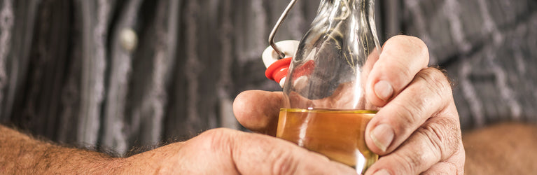 Des mains tiennent une bouteille d'huile de marmotte pure