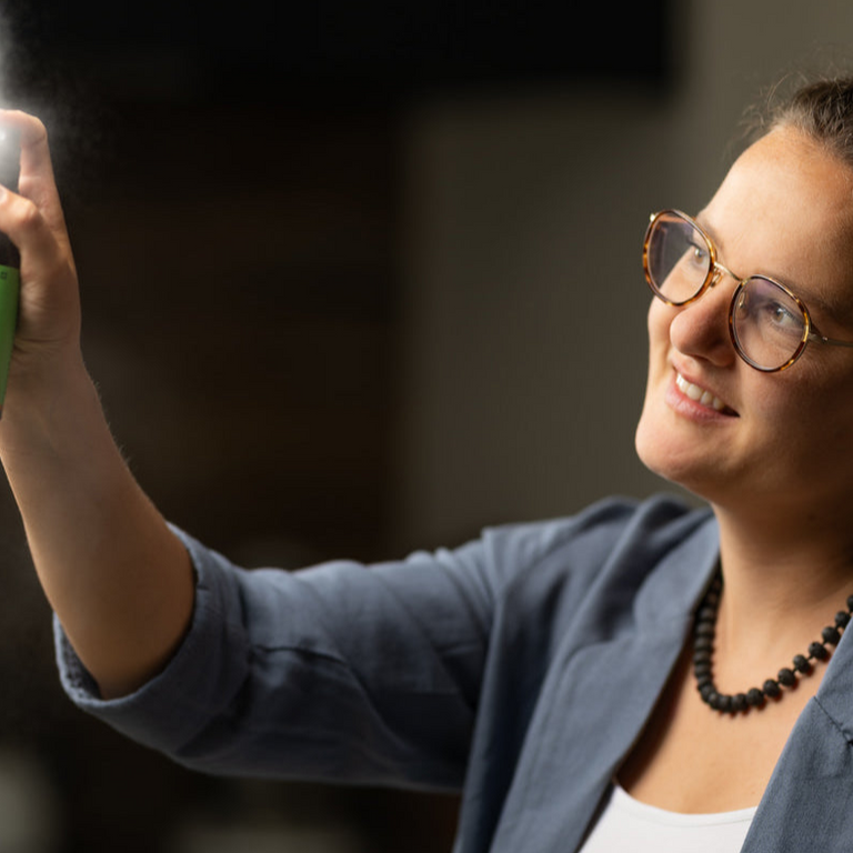 A person sprays Puralpina room fragrance into the room.