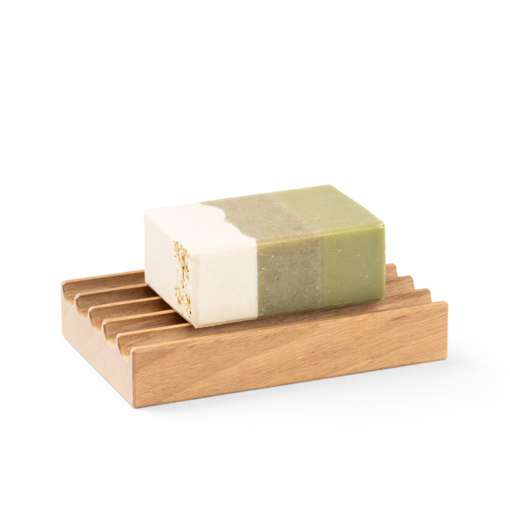 Savon naturel multicolore sur un porte-savon en bois de noyer suisse